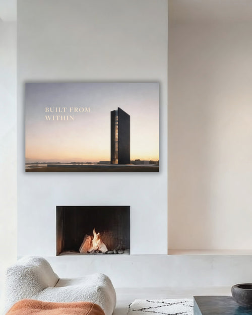 Statement Wandbild auf Alu-Dibond mit dem Statement "BUILT FROM WITHIN". Daneben ein dunkles und modernes Gebäude, das symbolisch für "BUILT" steht. Präsentiert und aufgehängt in einem modernen und minimalistischen Wohnzimmer über einem Kamin.