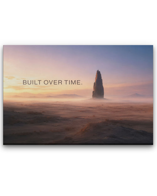 Leinwandbild „BUILT OVER TIME.“ von SuccessRemind mit monumentalem Fels in weiter Wüstenlandschaft bei warmem Morgenlicht.